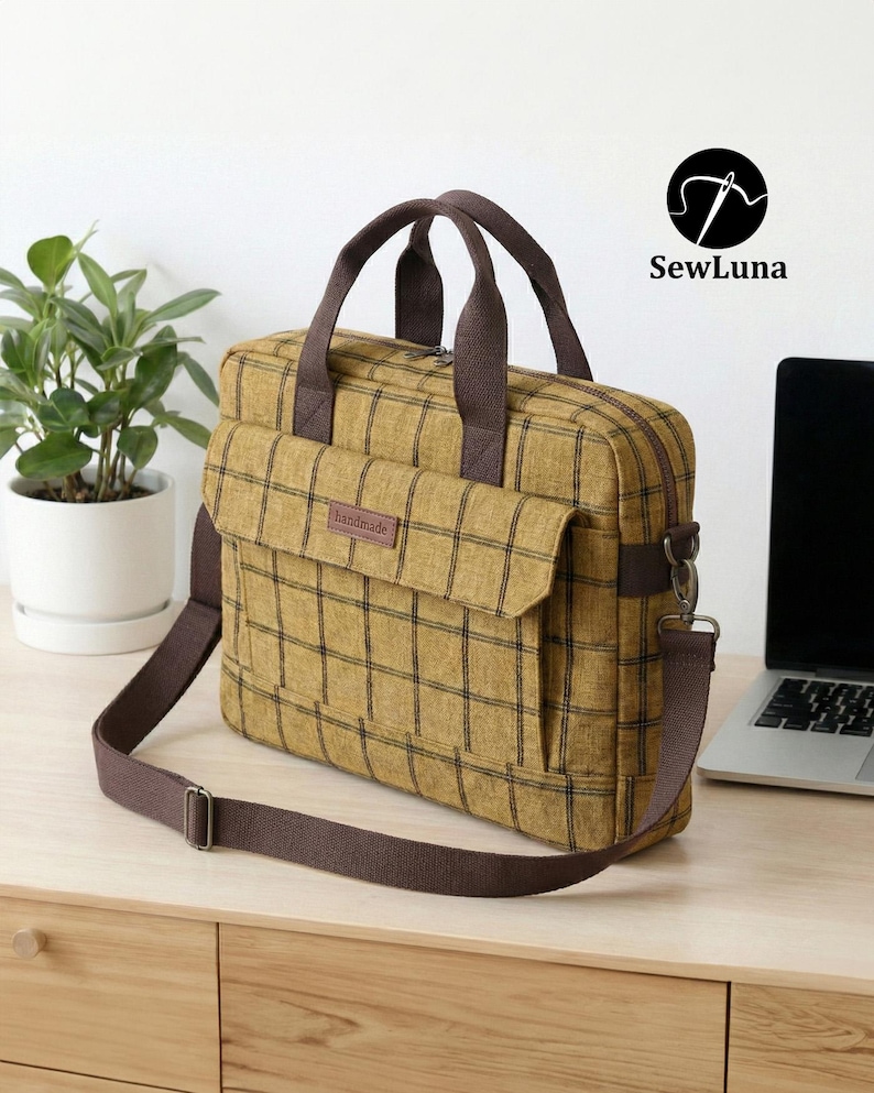 Mustard yellow plaid handmade laptop bag sewing pattern featuring brown webbing handles, an adjustable shoulder strap, a top zipper, and a front flap pocket, displayed on a clean white background.