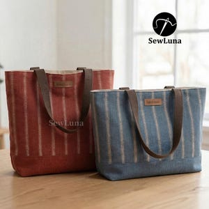 Może przedstawiać: Dwie torby typu tote z pionowymi paskami. Jedna jest czerwona, druga niebieska. Obie mają brązowe uchwyty i małą metkę "handmade". Torby leżą na drewnianej powierzchni. Widoczne jest logo SewLuna.