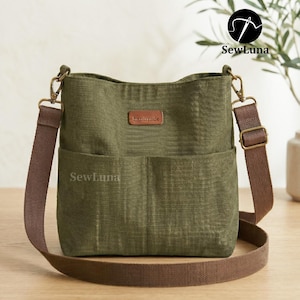 May include: Olive green crossbody bag with a brown adjustable strap and a front pocket. The bag has a leather tag that says "handmade". The brand name "SewLuna" is printed on the bag.