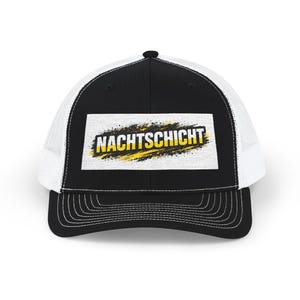 Könnte beinhalten: Schwarz-weiße Trucker-Cap mit einem rechteckigen Aufnäher mit dem Wort "NACHTSCHICHT" in Schwarz und Gelb. Die Cap hat einen schwarzen Schirm und eine Krone sowie eine weiße Mesh-Rückseite.