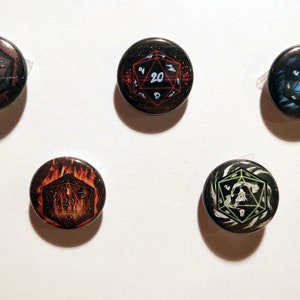 May include: Five round buttons with a D20 dice design. Each button features a different color scheme, including red, blue, and orange, with the number 20 prominently displayed. These buttons are likely for gaming enthusiasts.
