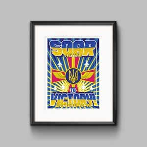 May include: Framed art print with a patriotic design. The artwork features the words "SOAR TO VICTORY" in yellow and blue, with Ukrainian text. The print includes a coat of arms, wings, and fighter jets, all set against a blue and yellow background.