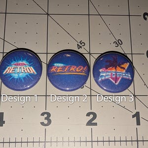 May include: Three circular pin-back buttons with a blue background, each measuring approximately 1 inch in diameter. The buttons feature the text "STAY RETRO!" in various graphic styles, including a sunburst, a neon-style font, and a palm tree.