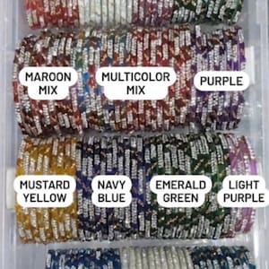 May include: A clear plastic container filled with stacks of colorful bangles. The bangles are in various colors, including red, white, lavender, green, maroon mix, multicolor mix, purple, mustard yellow, navy blue, emerald green, light purple, sky blue, silver white, and teal blue.