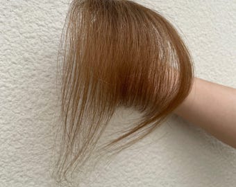 Flequillo castaño claro, ralo, con pinza y patillas.