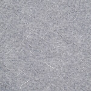 May include: Close-up of grey paper with white and black fibres. The paper has a textured surface with a random pattern of thin, curved lines. The overall appearance is soft and slightly mottled.