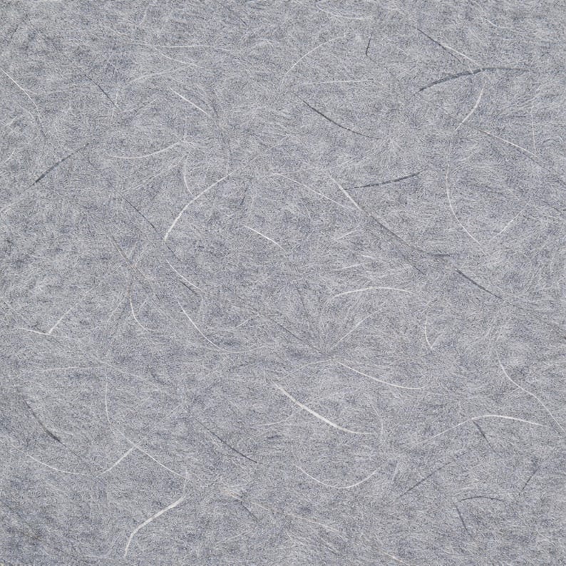 May include: Close-up of grey paper with white and black fibres. The paper has a textured surface with a random pattern of thin, curved lines. The overall appearance is soft and slightly mottled.