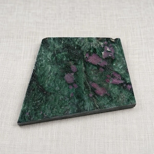 May include: A trapezoidal slab of polished zoisite stone featuring a deep forest green base color with prominent, irregular inclusions of vibrant magenta and deep purple ruby crystals scattered across the textured, natural mineral surface.