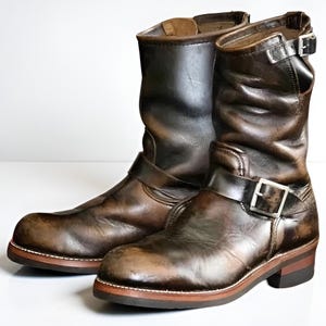 Puede incluir: Una taza de cerámica blanca con un asa negra y el texto "But First, Coffee" en negro, con una fuente de estilo manuscrito. La taza está sobre una superficie blanca.