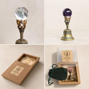 May include: A ritual bell featuring a clear or purple crystal sphere atop an ornate, antique-gold colored metal handle with leaf and gemstone accents. The set includes a brown cardboard gift box with a label reading Crystal Ritual Bell.