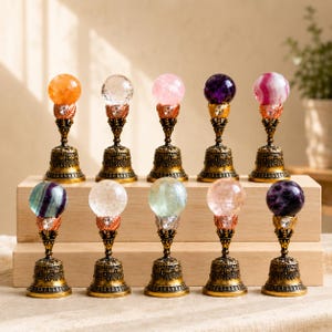 May include: Ten decorative wax seal stamps arranged in two rows. Each stamp features a spherical gemstone or glass orb topper in various colors, including orange, clear, pink, purple, and striped, mounted on an ornate, antique-style brass base.