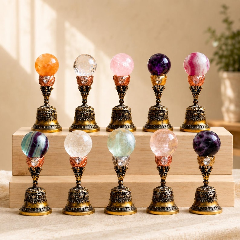 May include: Ten decorative wax seal stamps arranged in two rows. Each stamp features a spherical gemstone or glass orb topper in various colors, including orange, clear, pink, purple, and striped, mounted on an ornate, antique-style brass base.