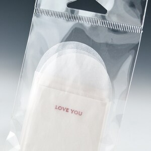 May include: A clear plastic bag with a white paper envelope inside. The envelope has the words "LOVE YOU" printed in red.