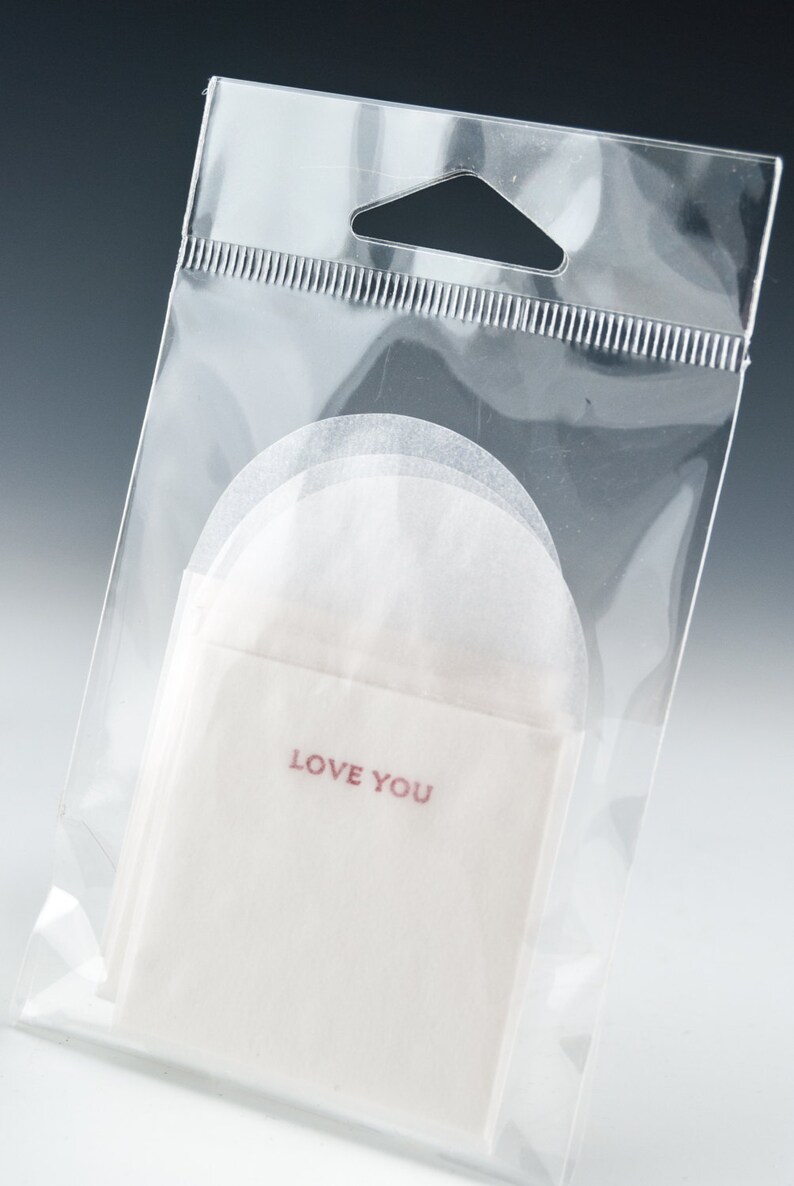 May include: A clear plastic bag with a white paper envelope inside. The envelope has the words "LOVE YOU" printed in red.