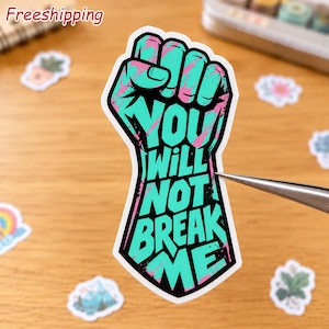 May include: A die-cut sticker shaped like a raised fist, featuring a vibrant teal and pink marbled pattern. The black text printed across the center of the fist reads, "YOU WILL NOT BREAK ME," in a bold, blocky, and slightly distressed font style.