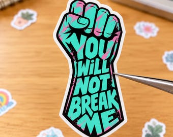 May include: A die-cut sticker shaped like a raised fist, featuring a teal and pink marbled pattern. The black text printed on the fist reads, "YOU WILL NOT BREAK ME," in a bold, capitalized, sans-serif font with a white border.
