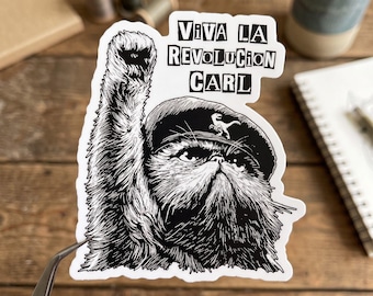 Könnte beinhalten: Ein schwarz-weißer Aufkleber mit einer flauschigen Katze, die ein Barett mit einem kleinen Dinosaurier-Symbol trägt und eine Pfote in die Luft hebt. Der Text über der Katze lautet VIVA LA REVOLUCION CARL in fetten, schwarzen Buchstaben.