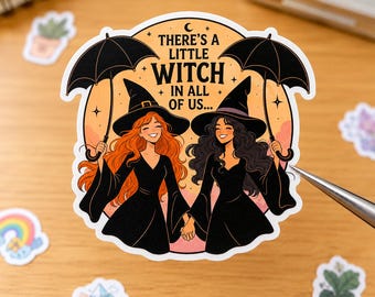 May include: A circular sticker featuring two smiling figures in black witch hats and dresses, each holding a black umbrella. The text reads, THERE'S A LITTLE WITCH IN ALL OF US... against a peach-colored background with small stars and a crescent moon.