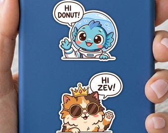 May include: Two die-cut stickers on a blue surface. The top sticker shows a blue creature in a space helmet waving with a speech bubble saying HI DONUT!. The bottom sticker shows a calico cat wearing a gold crown and sunglasses waving with a speech bubble saying HI ZEV!.