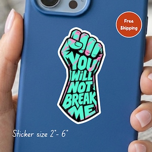 May include: A die-cut sticker featuring a raised fist graphic in teal and pink with the black text "YOU WILL NOT BREAK ME" integrated into the design. The sticker is displayed on a blue phone case with a visible size range of 2" to 6".