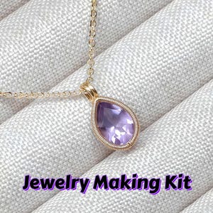 May include: A gold necklace with a teardrop pendant holding a light purple gemstone. The pendant is framed by gold wire. The text "Jewelry Making Kit" is displayed in purple.