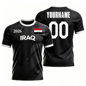 May include: Black soccer jersey with white trim and the text "IRAQ" and "2026". The front of the jersey features the Iraqi flag. The back displays "YOURNAME" and the number "00".