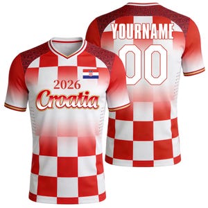 May include: A red and white chequered football shirt with the text "2026 Croatia" and the Croatian flag on the front. The back of the shirt has the text "YOURNAME" above the number "00". The shirt has red sleeves with gold trim.