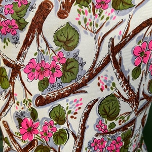 K&ouml;nnte beinhalten: Ein wei&szlig;er Stoff mit einem sich wiederholenden Muster aus rosa Bl&uuml;ten, braunen Zweigen und gr&uuml;nen Bl&auml;ttern.