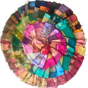 May include: A circular arrangement of small fabric pouches in a variety of colors, including pink, green, purple, and gold. Each pouch appears to be made from a different patterned fabric, creating a vibrant and diverse display. The pouches are likely for small gifts.