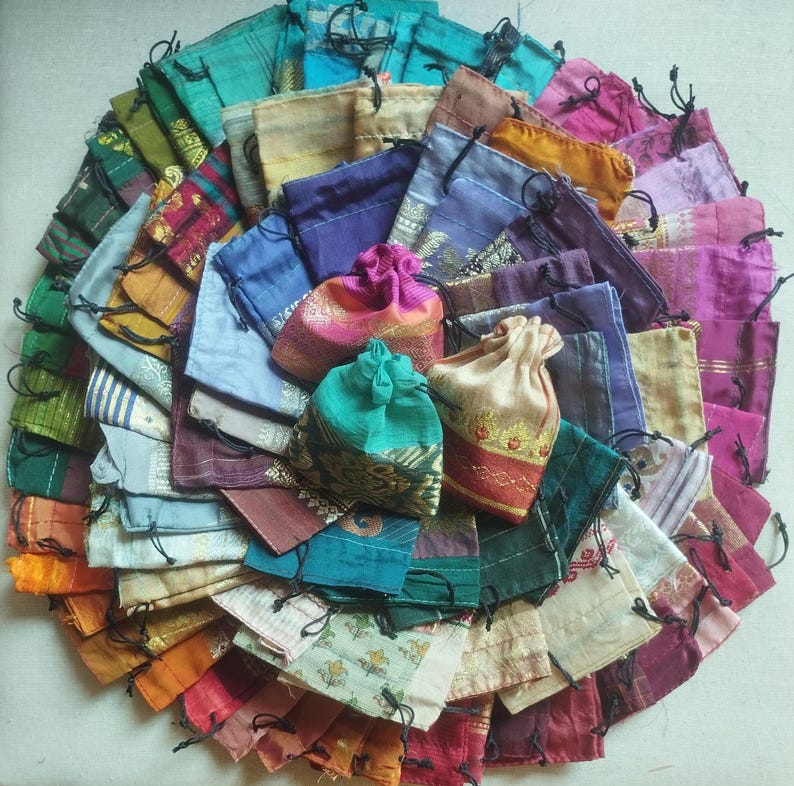 May include: A collection of colorful fabric drawstring pouches with various patterns and designs. The pouches are made of silk and are perfect for storing small items.