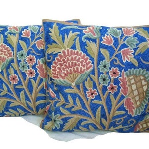May include: Two blue throw pillows with embroidered floral patterns in shades of pink, green, and brown.