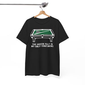 May include: Black t-shirt featuring a white and green graphic of a pool table with a rack of billiard balls and a cue stick. The text "THE GREEN FELT IS MY ONLY CONTINENT" is printed below the graphic.