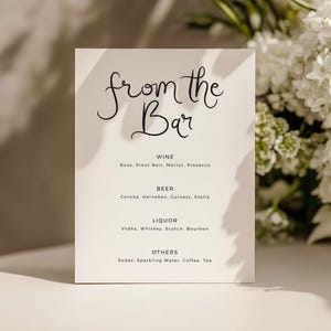 May include: A rectangular white menu card with black text that reads from the Bar, followed by categories for Wine, Beer, Liquor, and Others, listing various beverage options including Rose, Pinot Noir, Merlot, Prosecco, Corona, Heineken, and more.