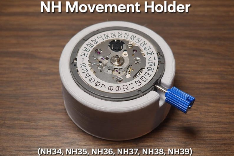 May include: A white NH Movement Holder with a watch movement inside. The watch movement has a silver face with black numbers and a blue tool. The text "NH Movement Holder" is at the top, and the model numbers are listed at the bottom.
