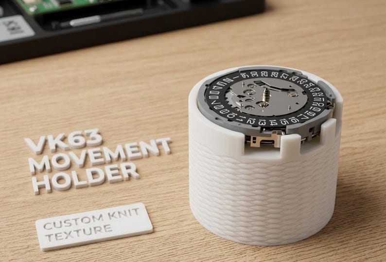 May include: A white VK63 movement holder with a custom knit texture, holding a watch movement. The watch movement has a silver face with black and white markings. The text "VK63 MOVEMENT HOLDER" and "CUSTOM KNIT TEXTURE" are also visible.