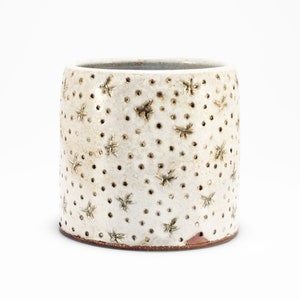May include: White ceramic planter with a textured surface featuring a pattern of small brown dots and star shapes.