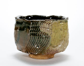 May include: A small, brown ceramic teacup with a textured, wavy design. The cup has a slightly uneven rim and a small foot.