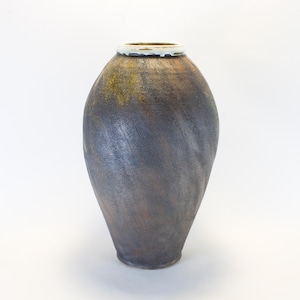 May include: A handcrafted, dark-toned ceramic vase with a textured surface. The vase has a wide, rounded body that tapers to a narrow base. The rim is accented with a white and green glaze. The vase is approximately 12 inches tall.
