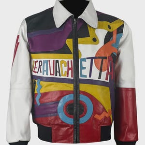 Puede incluir: Chaqueta de cuero colorida con cuello blanco y el texto "VERAVACHETTA". La chaqueta presenta una cremallera y puños negros, con paneles blancos, negros, morados, amarillos, rojos y naranjas. El diseño incluye formas y líneas geométricas.