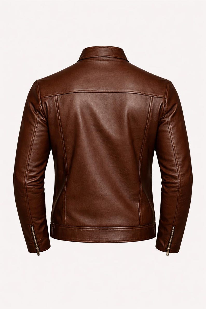 May include: A brown leather jacket with a classic design. The jacket features a collared neckline, a zipper closure, and zippers on the sleeves. The back of the jacket is visible, showcasing the tailored fit and stitching details.