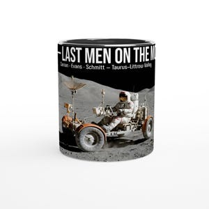 Może przedstawiać: Ceramiczny kubek z czarno-białym krajobrazem księżycowym i astronautą prowadzącym łazik księżycowy. Tekst głosi THE LAST MEN ON THE MOON Cernan - Evans - Schmitt - Taurus-Littrow Valley. Kubek ma czarne wnętrze i białą powierzchnię zewnętrzną.