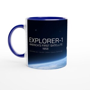 Pode incluir: Uma caneca de cerâmica com alça e interior azul escuro, apresentando um gráfico espacial da Terra a partir da órbita. O texto diz EXPLORER-1, AMERICA'S FIRST SATELLITE, 1958, Launch Vehicle: Juno I, Orbit 358 x 2550 km, Discovery: Van Allen Belts.
