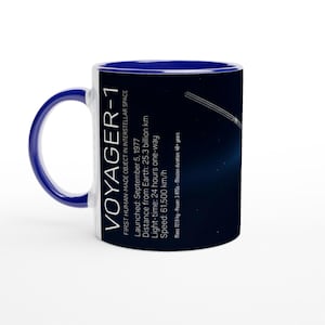 Könnte beinhalten: Weiße Voyager-1-Keramiktasse mit blauem Innenraum und Griff. Die Tasse zeigt Text und Grafiken zur Raumsonde Voyager-1, einschließlich Startdatum, Entfernung von der Erde und Geschwindigkeit. Ein tolles Geschenk für Weltraumfans.