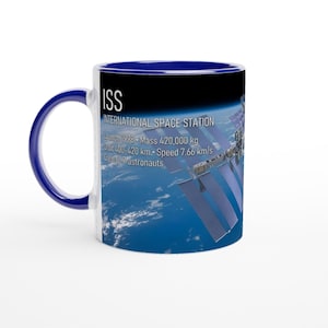 Peut inclure: Un mug en céramique blanc avec une anse et un intérieur bleu foncé. L'extérieur présente une image de la Station spatiale internationale en orbite autour de la Terre avec le texte : ISS INTERNATIONAL SPACE STATION, Launch 1998, Mass 420 000 kg, Orbit 400-420 km, Speed 7,66 km/s, Crew 6-7 astronauts.