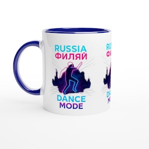 May include: White ceramic mug with a blue interior and handle. The mug features the words "RUSSIA ФИЛИАЙ" in teal and pink, along with a neon blue and purple silhouette of a person dancing. The words "DANCE MODE" are below the dancer.