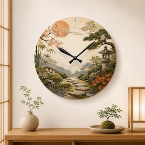 May include: A round wall clock featuring a printed landscape illustration of a stone path, a stone lantern, a bridge, bamboo, and a sun. The clock has black hour and minute hands set against a beige background with stylized wave patterns.