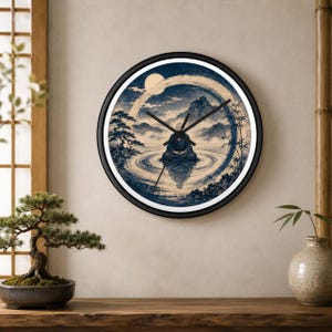 Op de afbeelding: Een ronde wandklok met een zwarte rand met een blauwe en beige illustratie van een persoon die op het water mediteert. De afbeelding bevat een grote cirkelvormige penseelstreek, bergen, bomen en een volle maan. Drie zwarte wijzers in het midden.