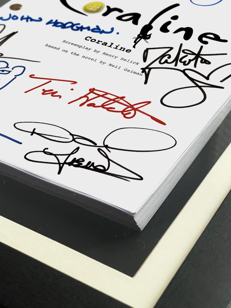 May include: A close-up of a book titled "Coraline" with multiple signatures in black, blue, and red ink. The book's title is in a stylized font, and the cover features the names of the screenplay writer and the author of the novel.