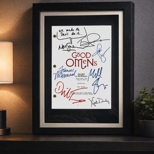 May include: Framed print featuring the title "Good Omens" with multiple signatures in blue and red ink. The print includes the text "We made the Devil do it..." and is set in a black frame with a white mat.