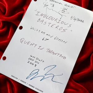 May include: A white ceramic mug with a black handle and the text "But first, coffee" in a black, handwritten-style font. The mug is on a white surface.